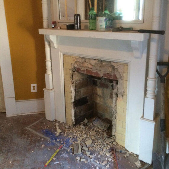 Work in progress: fireplace with painted mantel and tile surround partially removed exposing the brick firebox