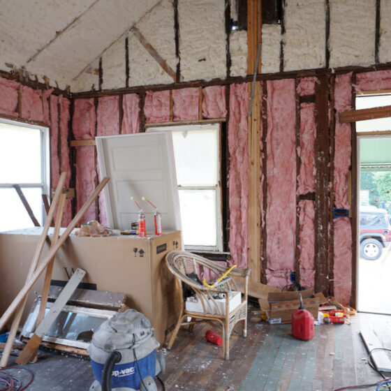 Before renovation: main room stripped to wall studs with new insulation and tools on the floor