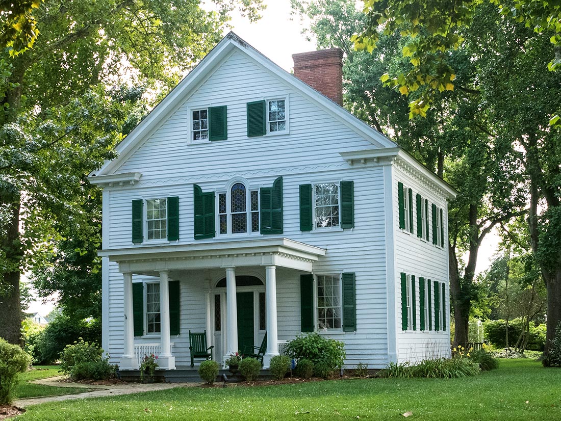 White Colonial home with green shutters and columned porch in Northeast Florida
