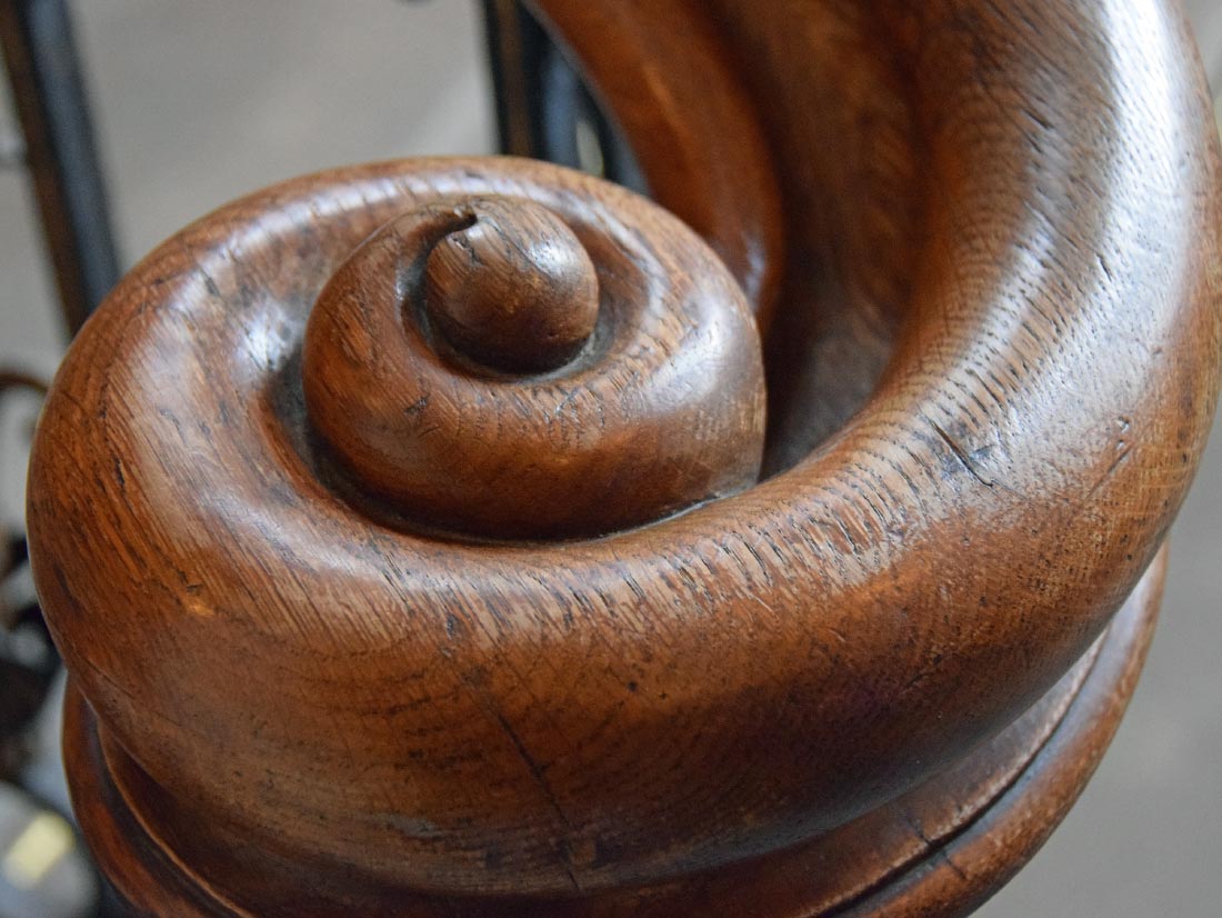 Carved wood staircase newel post detail representing craftsmanship and historic restoration, M&M Homes