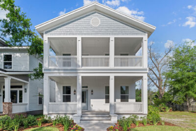 New construction two story home with stacked front porches and a gable roof in a Jacksonville neighborhood
