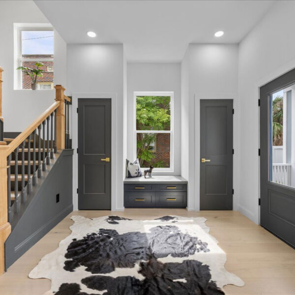 Entry foyer of a new home showing a staircase built in bench seat and light wood plank flooring