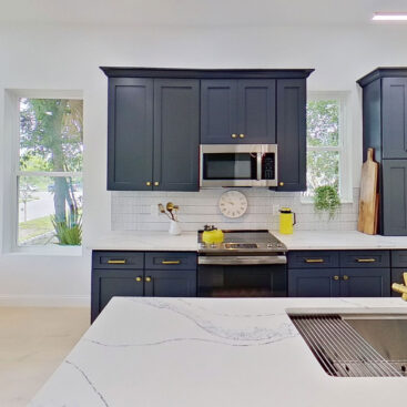 Kitchen range wall with a gold faucet and undermount sink viewed across the island of this new home design