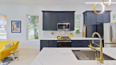 Kitchen range wall with a gold faucet and undermount sink viewed across the island of this new home design