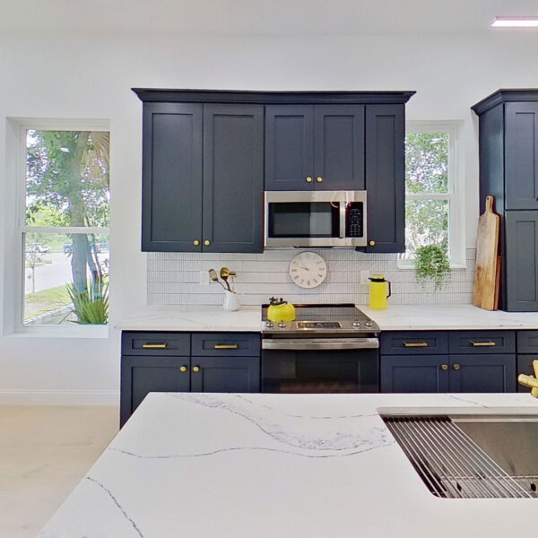 03-magnolia-kitchen-range-wall-gold-faucet-sink Kitchen range wall with a gold faucet and undermount sink viewed across the island of this new home design