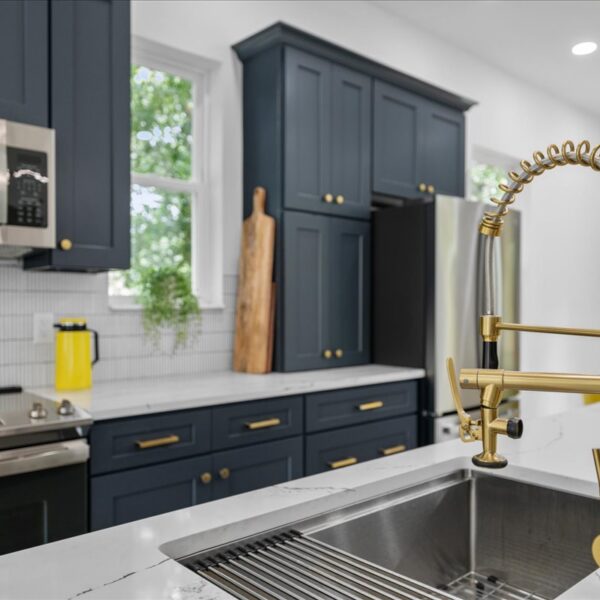 Close up of a gold spring faucet and undermount sink set in a veined white kitchen countertop