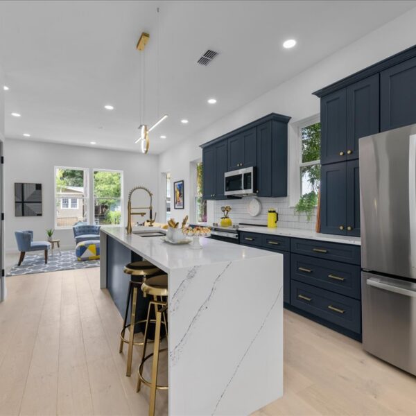 Kitchen island and stainless refrigerator with an open sight line to the living area beyond