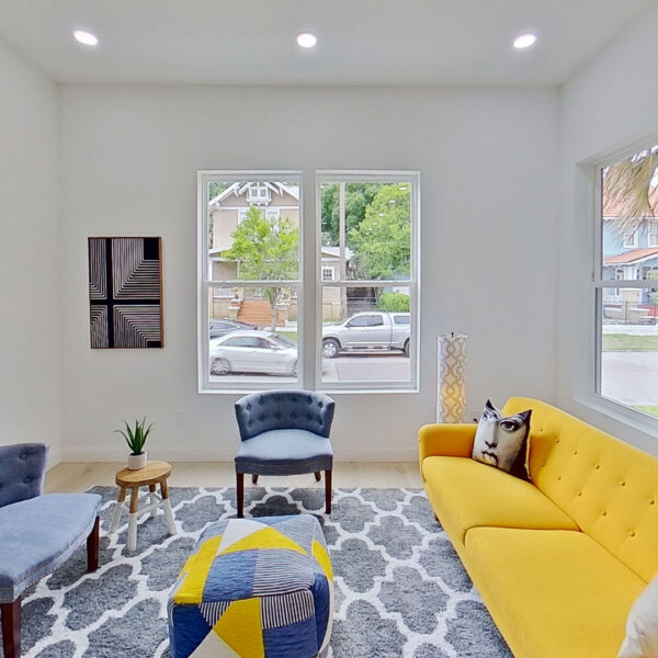 06-magnolia-front-sitting-room-yellow-sofa-windows Front sitting room with a yellow sofa and tall windows framing the surrounding historic neighborhood