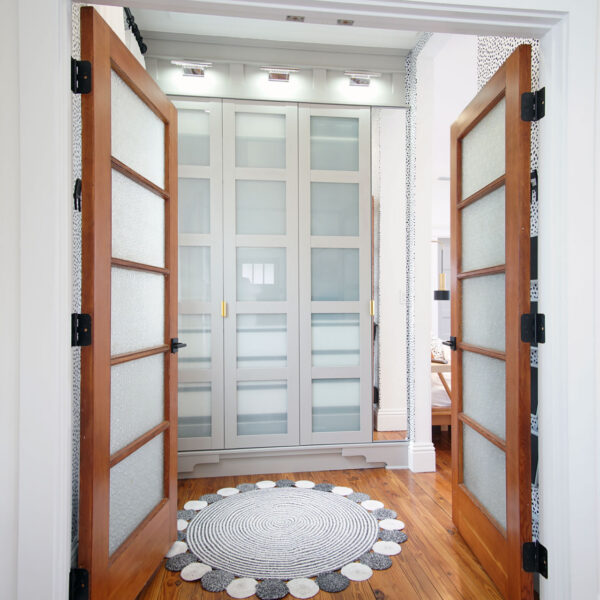 07-shotgun-house-wood-glass-double-doors-passage Paired wood doors with frosted glass panels open onto a passage lined with built in storage cabinets