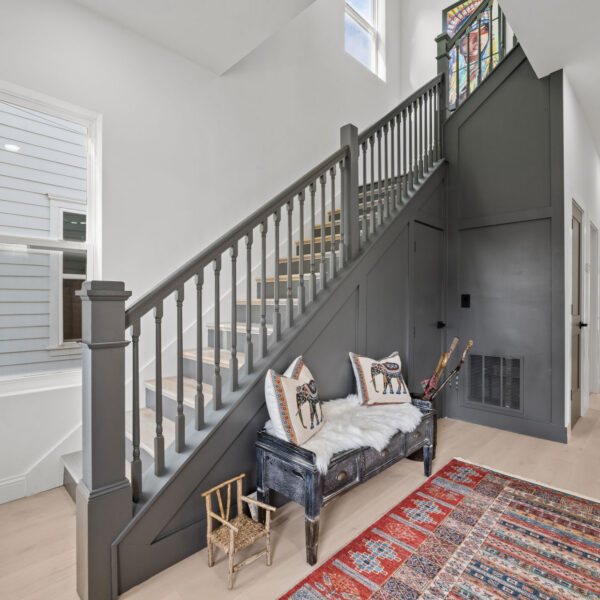 Painted staircase with turned balusters rising through a two story hall filled with daylight