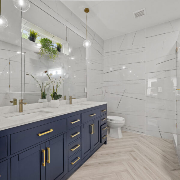 Bathroom with a navy double vanity large format marble look tile and a glass walk in shower