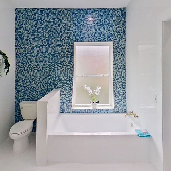 09-magnolia-bathroom-blue-mosaic-tile-soaking-tub Bathroom featuring a blue mosaic tile accent wall behind a built in soaking tub and frosted window