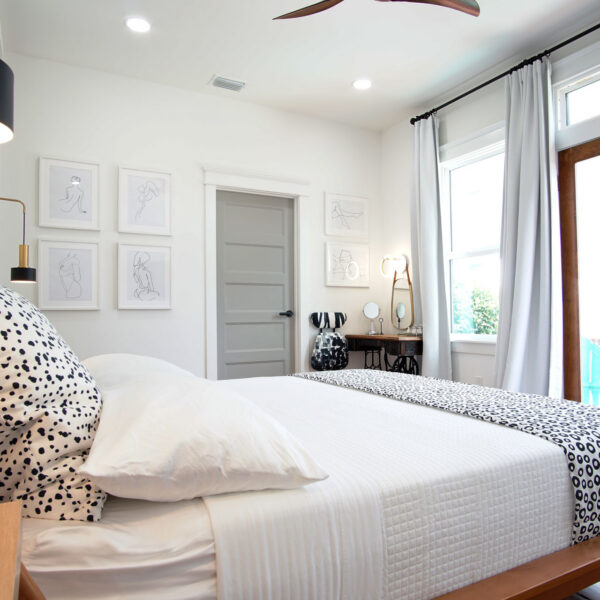 10-shotgun-house-bedroom-gallery-wall-vanity-corner Bedroom corner showing framed line drawings a small writing vanity and doors leading out to the deck