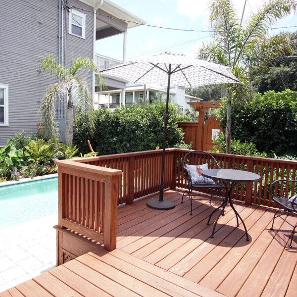 12-shotgun-house-pool-deck-bistro-seating-umbrella Wood deck with bistro seating and a shade umbrella overlooking the long private pool below