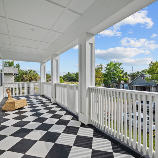 Second floor porch with black and white checkerboard tile flooring and a white railing above the street