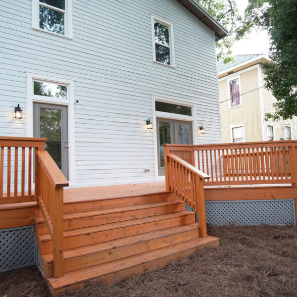 17-classic-colonial-rear-deck-exterior Rear elevation of the home with a wood deck and wide stairs down to the yard