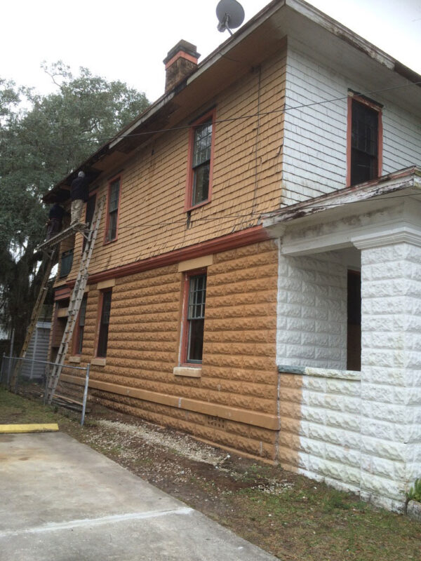 fireplace-house-during-side-elevation-shingles-stripped-jacksonville-mnm-homes-01-02 Work in progress: exterior with workers on ladders and side wall shingles partially stripped and recoated