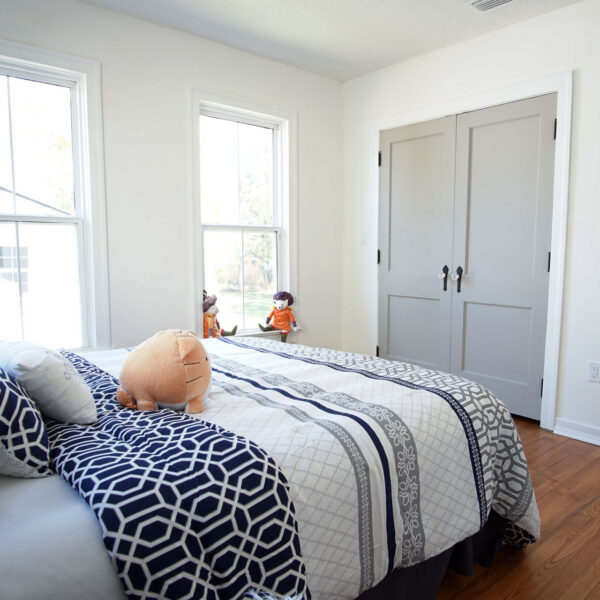 modern-farmhouse-bedroom-closet-doors-jacksonville-mnm-homes-13 Bedroom corner showing paneled double closet doors with dark hinges and vintage style glass knobs