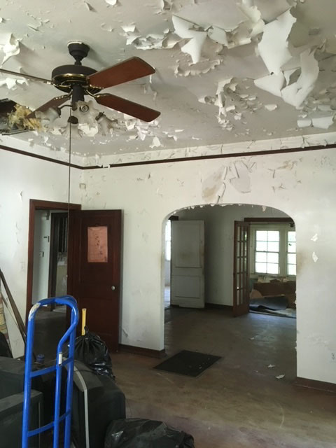 modern-farmhouse-during-peeling-paint-living-room-jacksonville-mnm-homes-07-04 Work in progress: heavily peeling ceiling and wall paint in a room with an arched opening and bare floor
