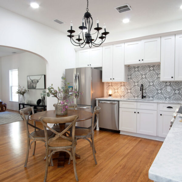 modern-farmhouse-eat-in-kitchen-jacksonville-mnm-homes-03 Eat in kitchen with white cabinetry patterned tile backsplash and an arched opening to the living room