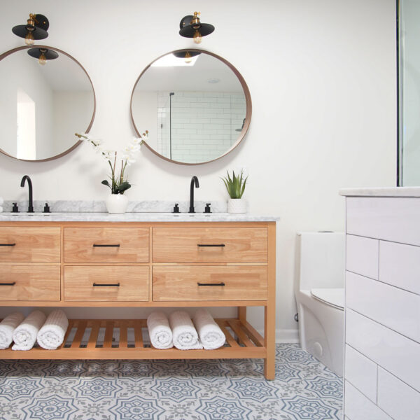 modern-farmhouse-ensuite-double-vanity-jacksonville-mnm-homes-09 Double vanity with two round mirrors black sconces and patterned floor tile in the ensuite bathroom