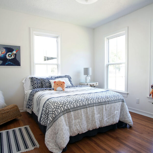 modern-farmhouse-guest-bedroom-jacksonville-mnm-homes-12 Guest bedroom with three tall windows crisp white trim and warm hardwood flooring underfoot