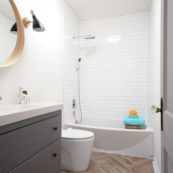 modern-farmhouse-hall-bathroom-jacksonville-mnm-homes-14 Compact hall bathroom finished with white subway tile a gray vanity and wood look herringbone floor