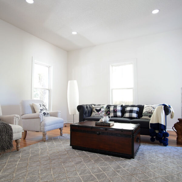 modern-farmhouse-living-room-jacksonville-mnm-homes-06 Sunlit living room with tall windows white walls and honey toned wood floors staged with striped armchairs