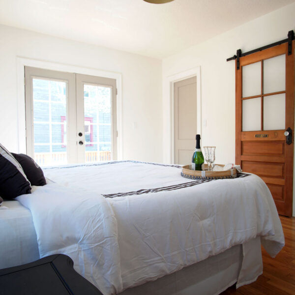 modern-farmhouse-primary-suite-ensuite-jacksonville-mnm-homes-08 Primary bedroom with a paneled wood door on a sliding track opening to the private ensuite bathroom