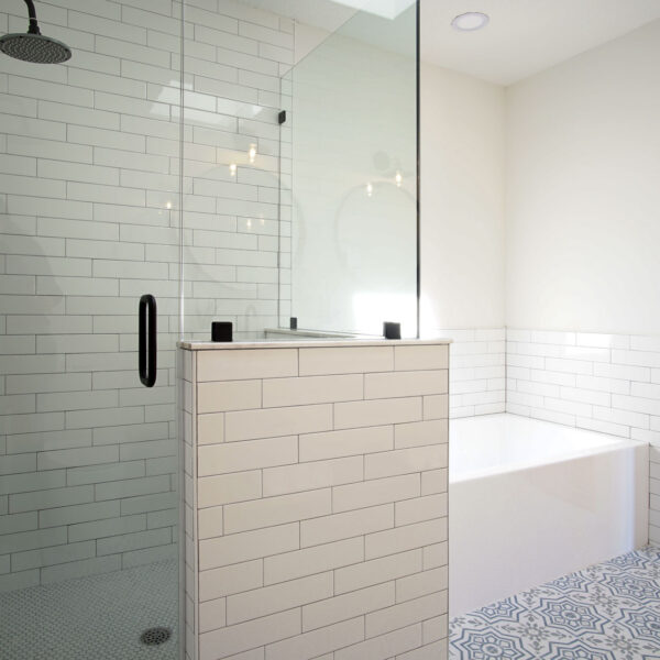 modern-farmhouse-walk-in-shower-skylight-jacksonville-mnm-homes-11 Walk in shower beside a corner tub with daylight from a skylight overhead and hardwood beyond the door