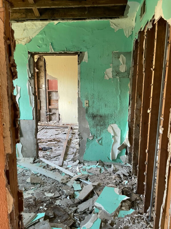 zen-garden-during-stripped-plaster-interior-jacksonville-mnm-homes-05-04 Work in progress: interior room with peeling paint and stripped wall framing above scattered debris