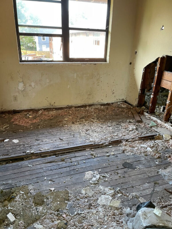 zen-garden-during-stripped-room-original-wood-floor-jacksonville-mnm-homes-05-08 Work in progress: bare room with debris on original wood flooring and an opened wall beside a window