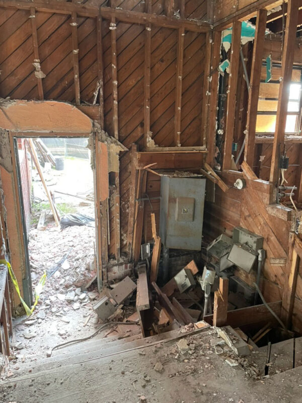 zen-garden-during-stripped-stairwell-electrical-panel-jacksonville-mnm-homes-05-07 Work in progress: interior stripped to board sheathing with an old electrical panel and loose debris